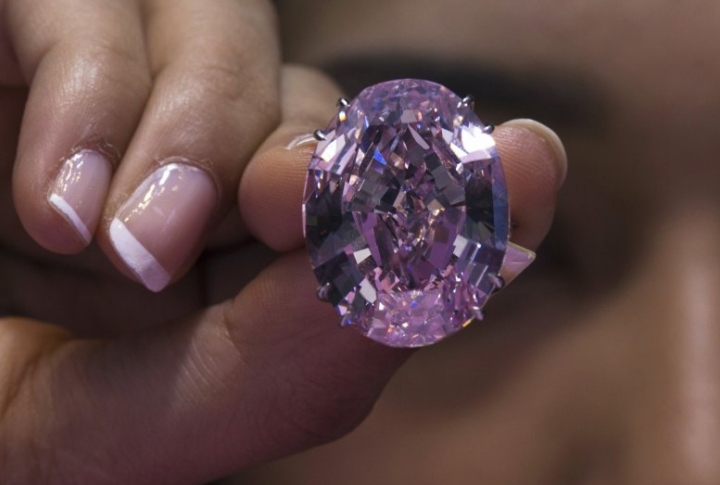 Модель позирует с бриллиантом Pink Star во время пресс-показа на аукционе Sotheby's в Гонконге 3 октября 2013 года. Огромный и редкий розовый алмаз, который весит 59,60 карата, может принести более 60 миллионов на аукционе в ноябре. ©REUTERS