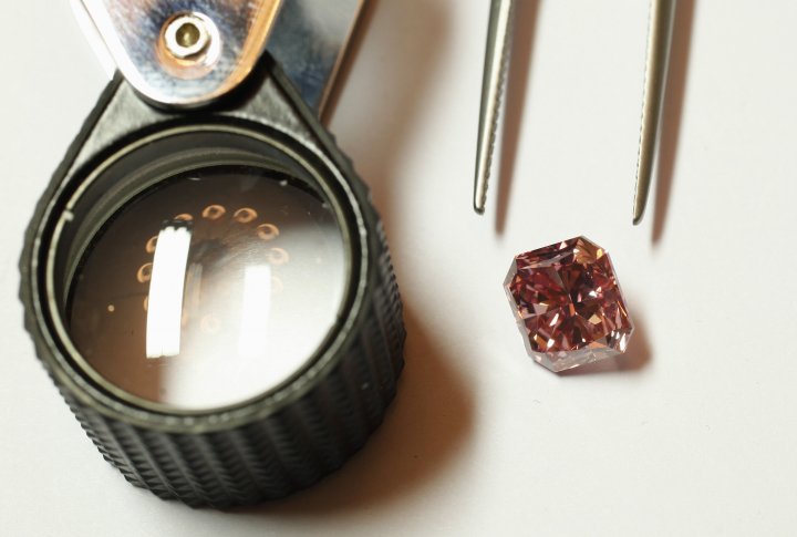Розовый бриллиант из шахты Rio Tinto на северо-западе Австралии на столе, с пинцетом и лупой. Представлен в Гонконге 6 сентября 2013 года. ©REUTERS