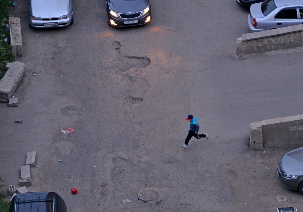 Напротив играют дети. То и дело мяч выкатывается на дорогу. Фото Турар Казангапов©