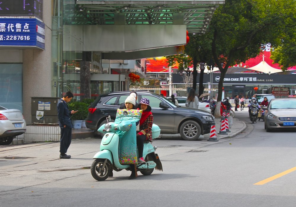 Кстати, в Китае для водителей скутеров шьют интересные и полезные аксессуары - это специальное одеяльце и варежки для езды в прохладное время суток, а также зонты, защищающие от дождя и солнца. Кроме того, на перекрестках можно увидеть такие шатры, под которыми стоят мопедисты  в ожидании зеленого сигнала светофора. Шатры защищают от пекла и осадков. Фото Роза Есенкулова ©