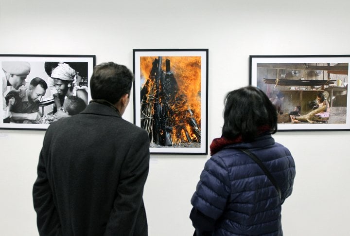 Гости выставки обсуждают фотографию из города Джуба, Судан. Груда винтовок горит при запуске программы ООН по разоружению, демобилизации и реинтеграции на юге Судана. 10 июня 2009 года