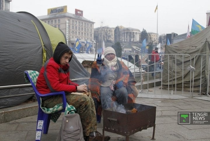 The damp weather is not enough to  chill down the protesters, but still they enjoy basking at the fire. ©Vladimir Prokopenko