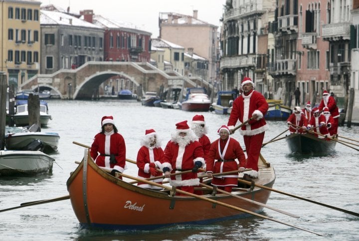 People dressed as Santa Claus row boats on the Venice canal in Italy. © Reuters/Manuel Silvestri