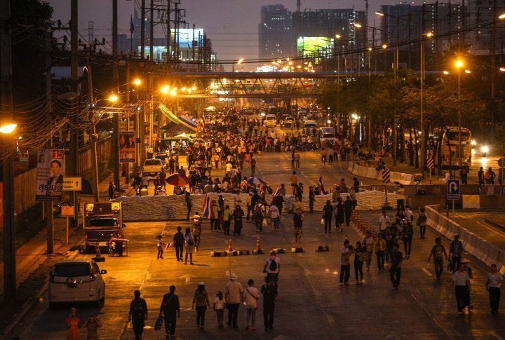 Anti-government protesters walk past a barricade as they block the road at the major intersection near the government complex in Bangkok. ©Reuters