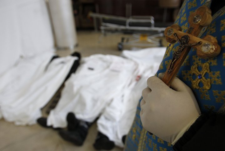 A priest standing near dead bodies after clashes between protestors and police. ©Reuters