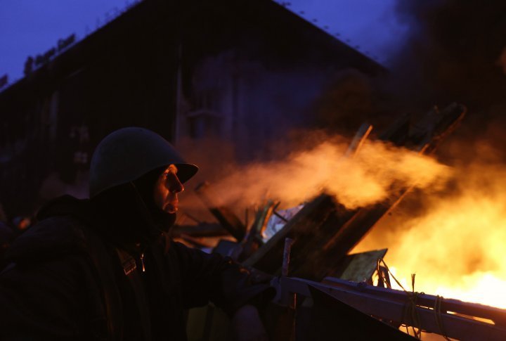 An anti-government demonstrator smocking on a barricade at the Independence Square in Kiev. ©Reuters