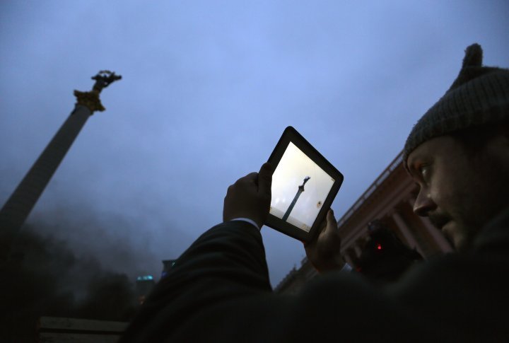 An anti-government demonstrator taking pictures on a barricade at the Independence Square in Kiev. ©Reuters