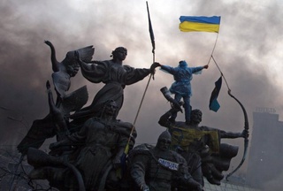 Anti-government protester waving a flag from the top of a statue during clashes with riot police in the Independence Square in Kiev. ©Reuters