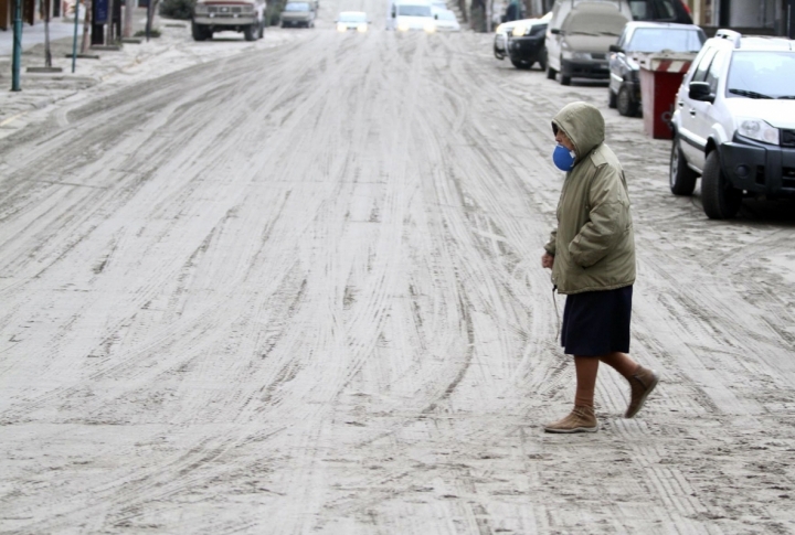 A woman walking across the street covered with volcanic ash. ©REUTERS/STRINGER Argentina