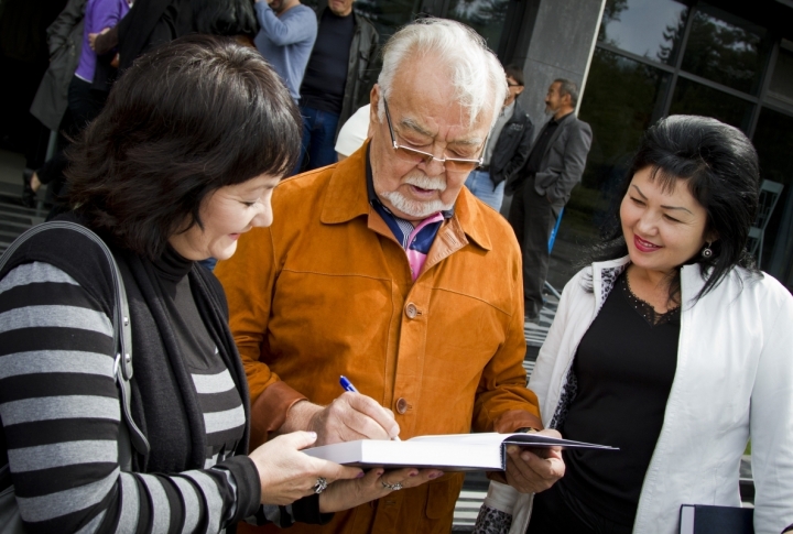 Maestro of Kazakhstan cinema Assanali Ashimov giving autographs in one of MOVIE encyclopedias of Kazakhstan. <br>Photo by Vladimir Dmitriyev©