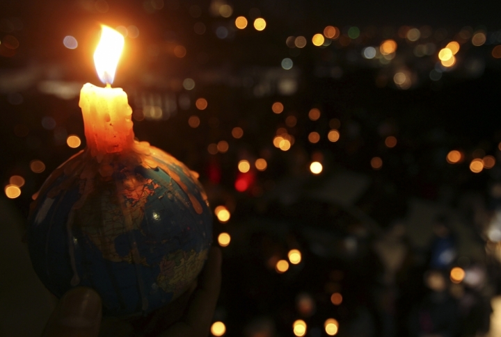 People hold candles during Earth Hour after lights were turned off in central Amman, Jordan. ©REUTERS/Ali Jarekji