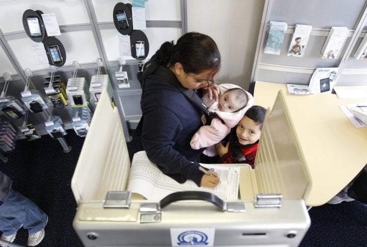 A Chicago voter casts her vote with her two children at a polling place in a U.S. cellular store during the U.S. presidential election in Chicago. ©REUTERS/Jeff Haynes