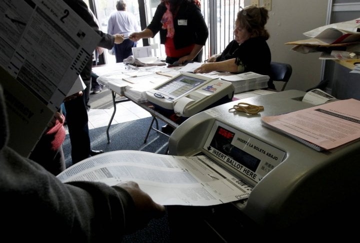 A Chicago voter places her ballot in the voting machine at the polling place in a U.S. Cellular store during the U.S. presidential election in Chicago. ©REUTERS/Jeff Haynes