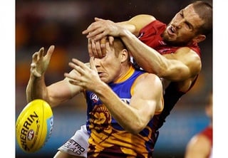 Ryan Harwood of the Lions gets dragged down by James Magner of the Demons as they compete for a mark during the Australian Rules Football match. Photo courtesy of SI.com