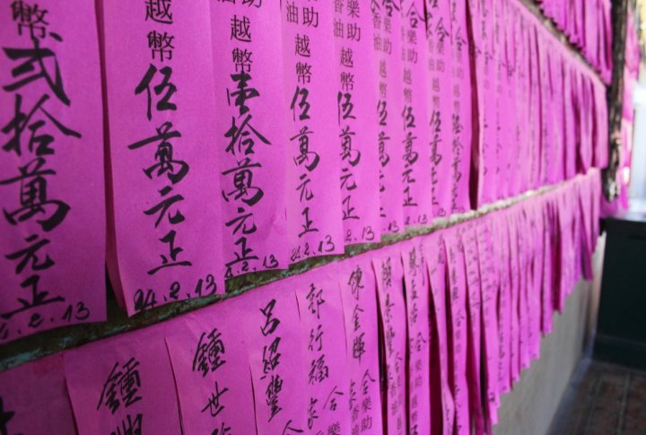 The temples in Ho Chi Minh City hang out the names of the people who donated money for charity. Photo by Roza Yessenkulova©