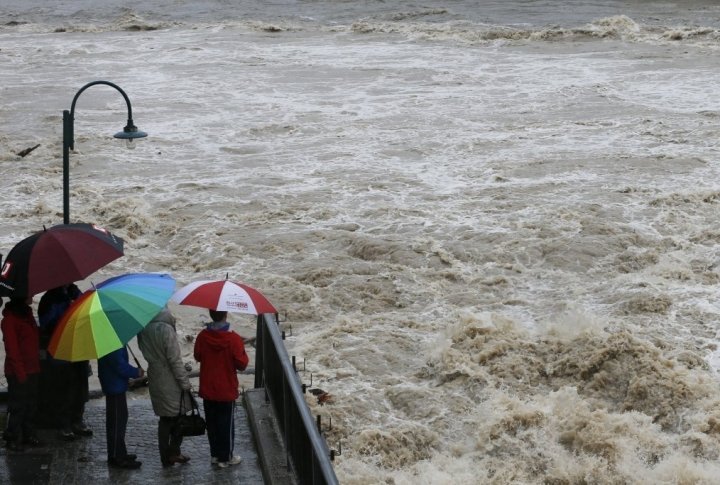 People stand next to a bridge and watch the flooding of river Steyr during heavy rainfall in the small Austrian city of Steyr. ©REUTERS