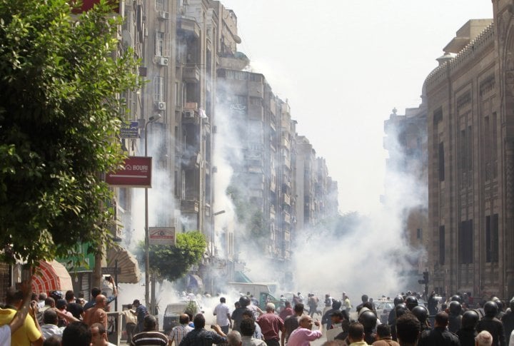 Supporters of ousted Egyptian President Mohamed Mursi run away from tear gas while local residents are seen in the foreground during clashes in central Cairo August 13, 2013. ©REUTERS