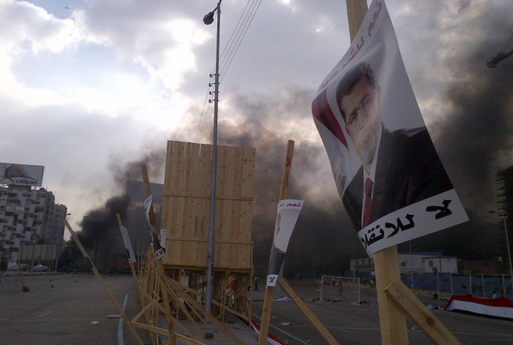 A poster of deposed Islamist President Mohamed Mursi is pictured in front of rising smoke during clashes between riot police and members and supporters of the Muslim Brotherhood. ©REUTERS