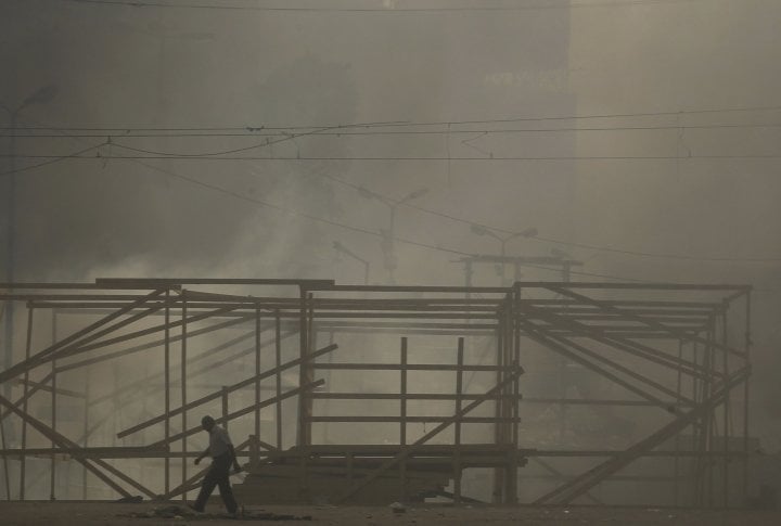 Members of the Muslim Brotherhood and supporters of deposed Egyptian President Mohamed Mursi walk amidst smoke at Rabaa Adawiya square, where they are camping, in Cairo August 14, 2013. ©REUTERS