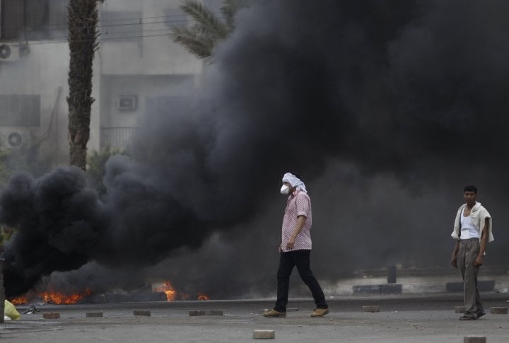 Members of the Muslim Brotherhood and supporters of deposed Egyptian President Mohamed Mursi walk near smoke from a fire at Rabaa Adawiya square, where they are camping, in Cairo August 14, 2013. ©REUTERS