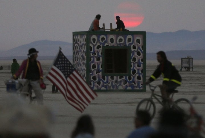 Participants watch the sunrise from atop an art installation. ©REUTERS