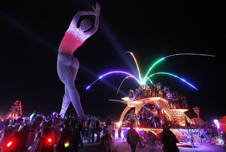 Participants dance around and atop an art car parked beside the "Truth is Beauty" sculpture. ©REUTERS