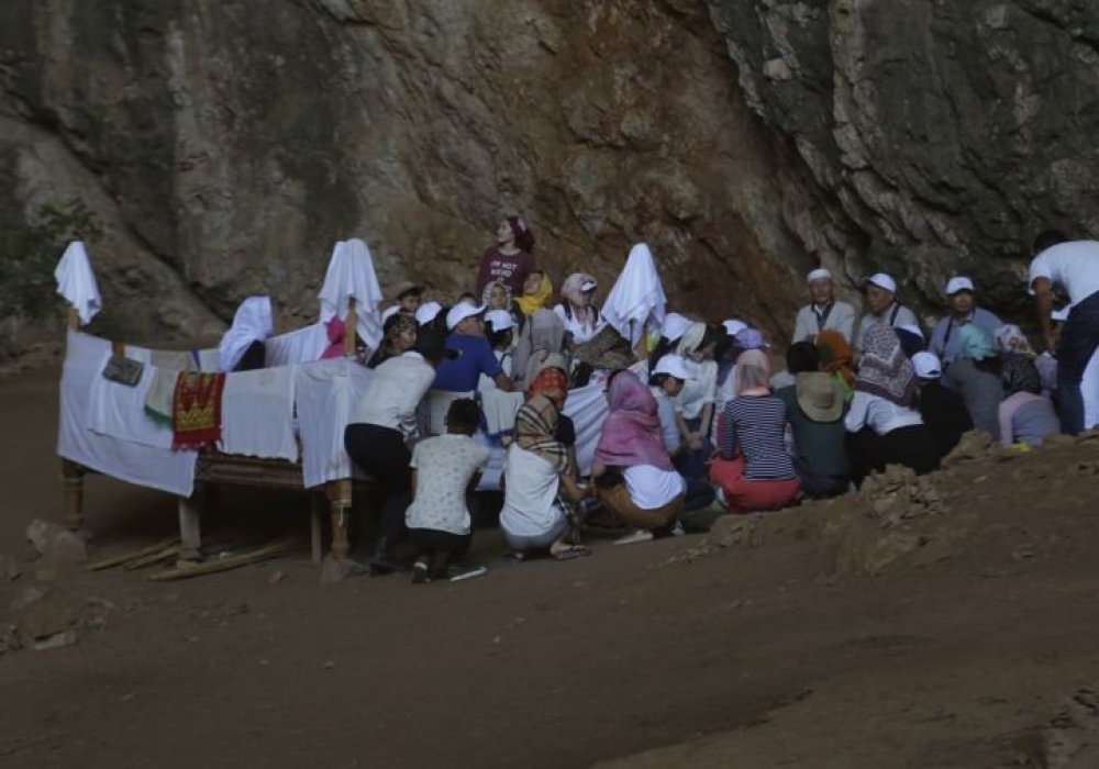 Үңгірдің ішінде осы бір киелі мекенге зиярат етушілерге таныстырып, дұға бағыштайтын Асқар ақсақал отырады. Талай ғасыр бұрын он мың әскер сыйған жерге бүгінде ақ маталар жайылып, тапшан қойылған екен.