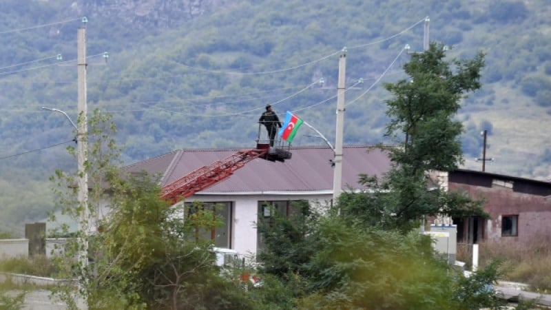 Мужчина устанавливает флаг Азербайджана в одном из населенных пунктов Нагорного Карабаха. © РИА Новости