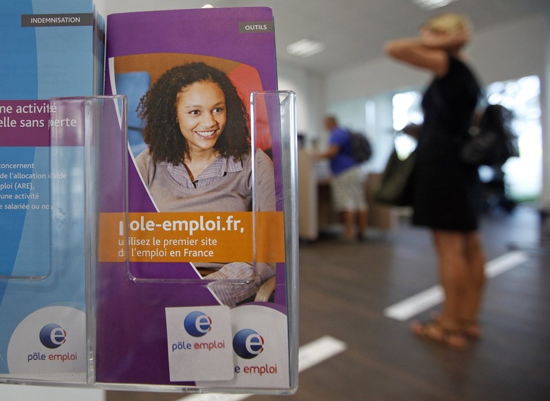 A job seeker stands near information leaflets for jobs. ©REUTERS/Eric Gaillard 