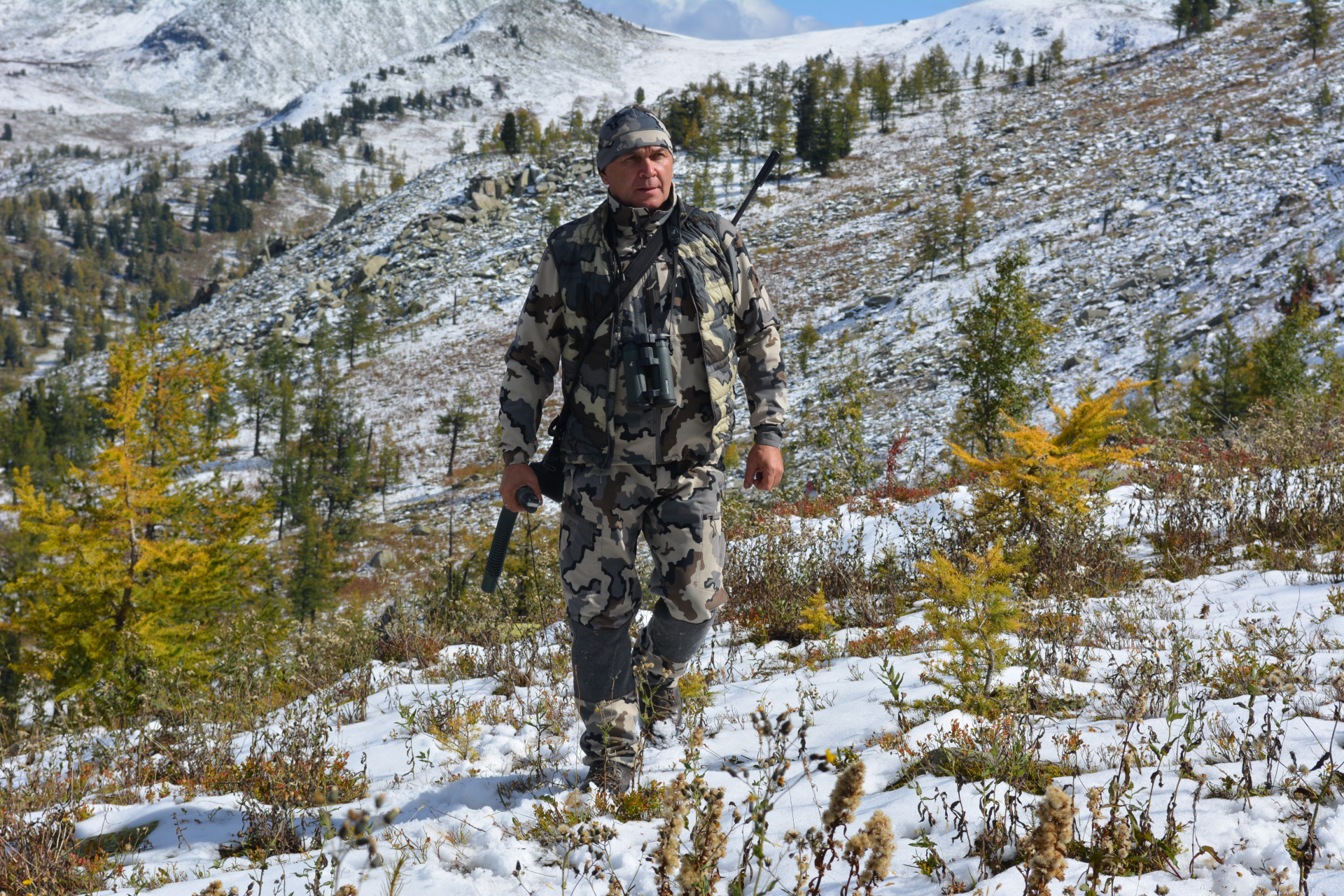 Евгений Сидельников идёт по склону с оружием