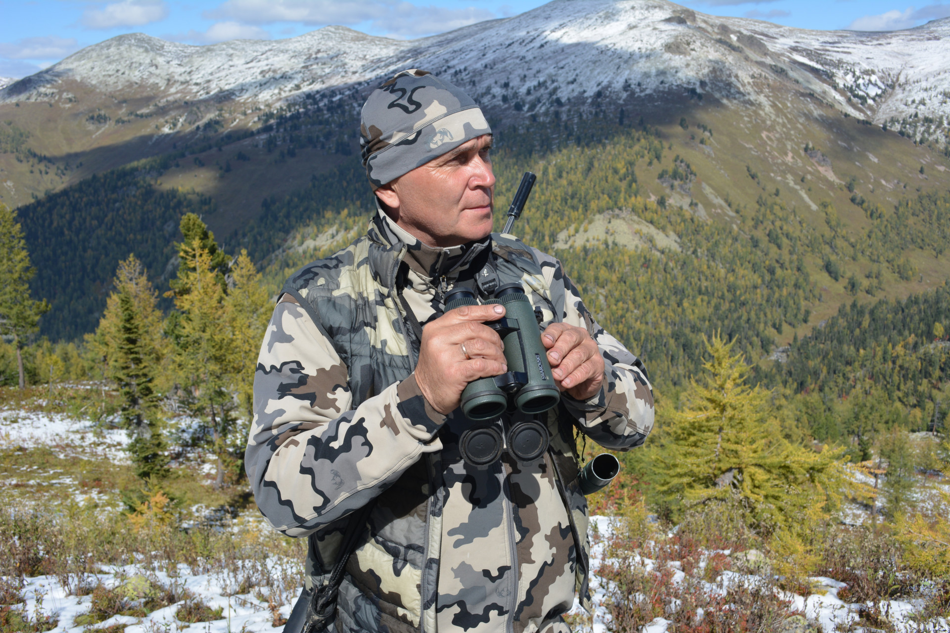 Охотовед Евгений Сидельников с биноклем в горах