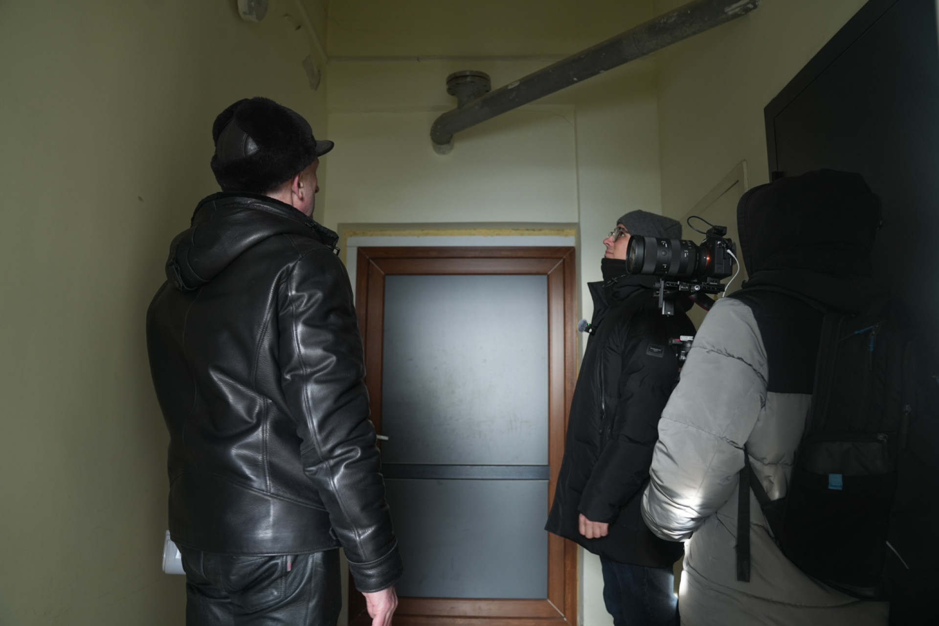 Председатель ОСИ и съемочная группа к двери, ведущей на  "техэтаж" в ЖК "Жайлау"