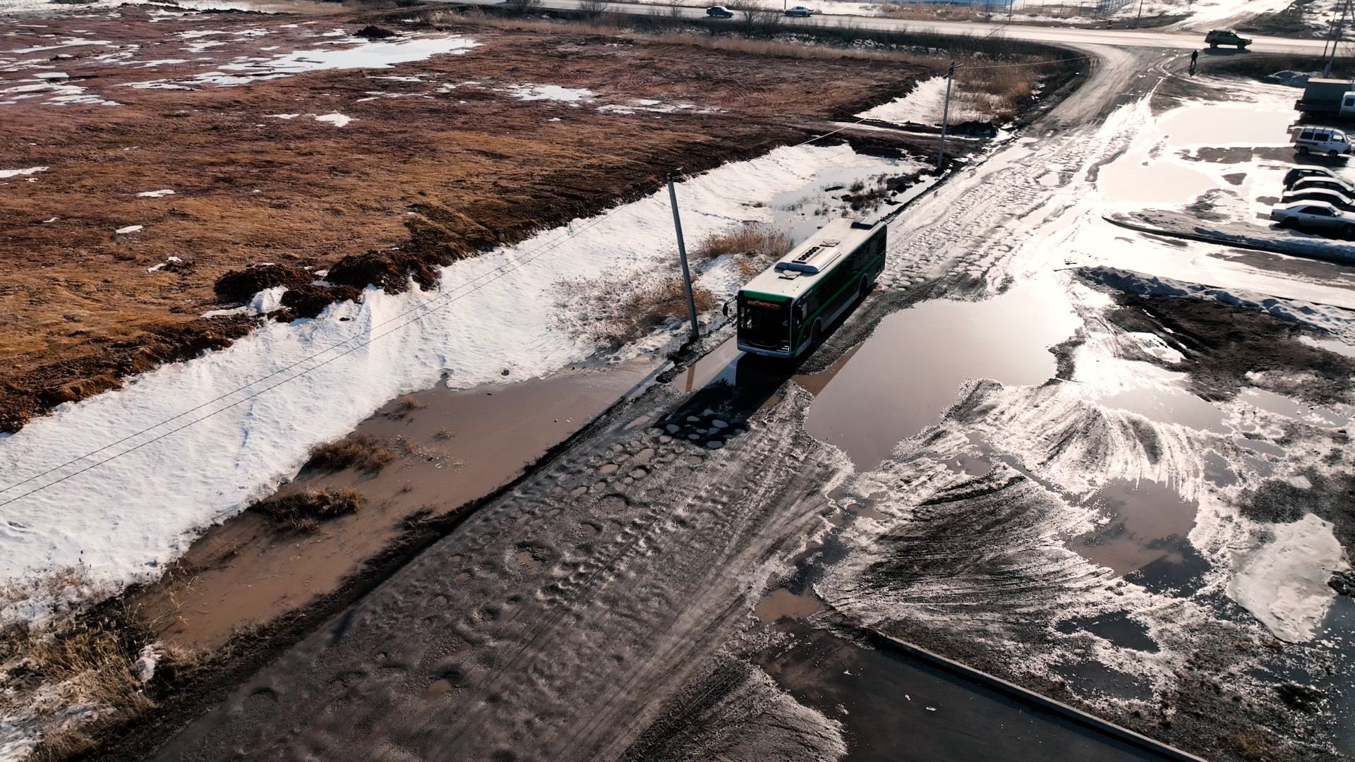 Автобус едет по разбитой дороге, которая вся в грязи, массив Нефтяников