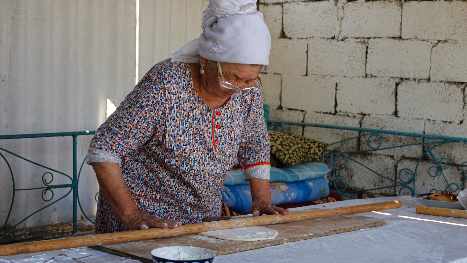Пожилая женщина раскатывает тесто