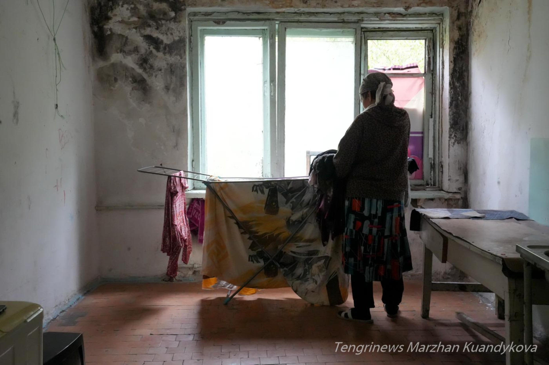 Женщина вешает белье в постирочной аварийного общежития на Пастера в Астане. 