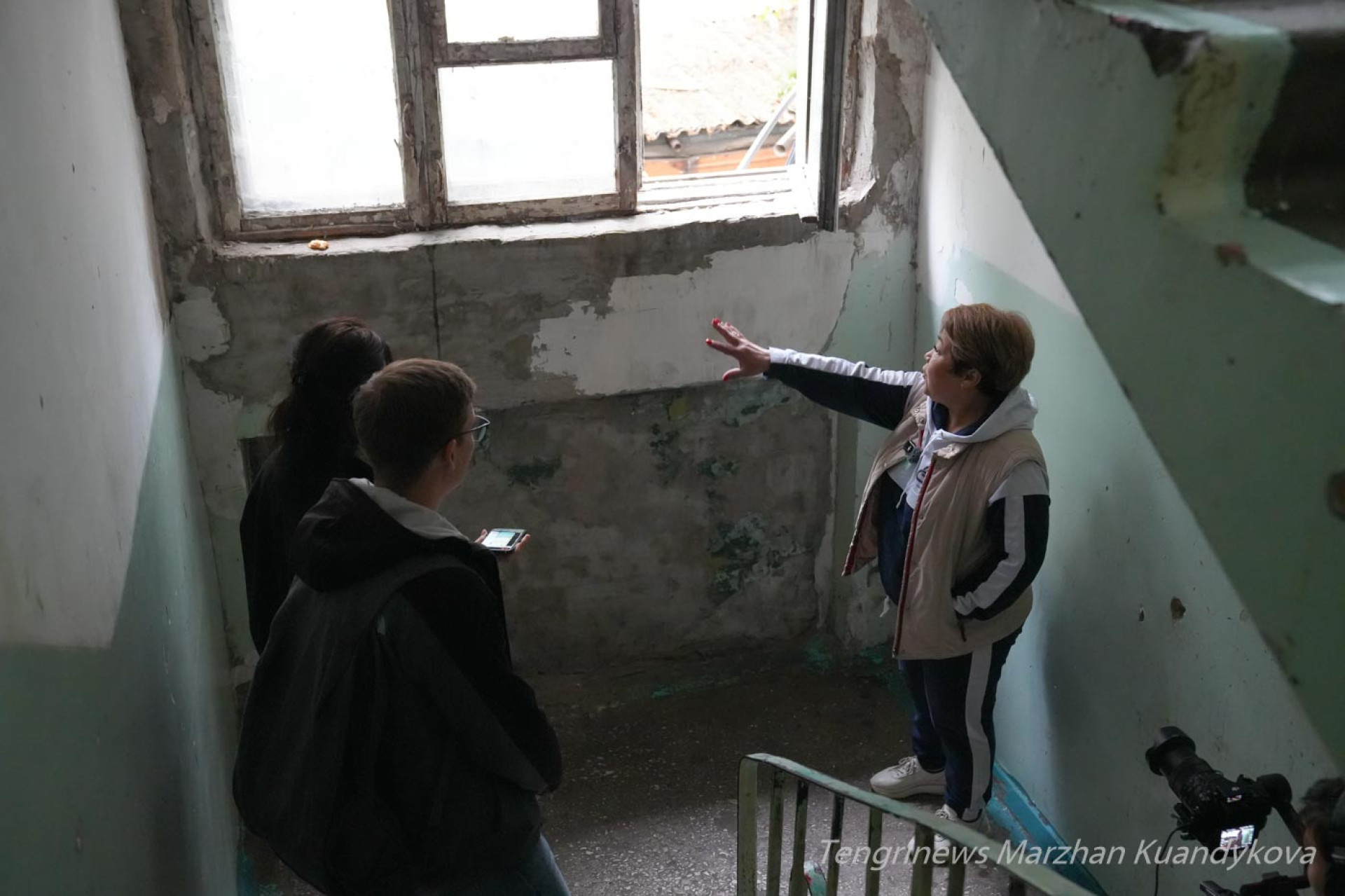 Гульбарам, старшая по дому, показывает облупившиеся стены варийного общежития на Пастера в Астане