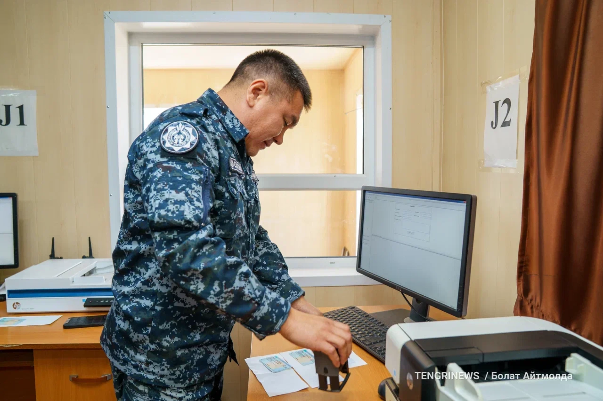 Сотрудник погранслужбы Казахстана ставит печати о пересечении границы в паспорта