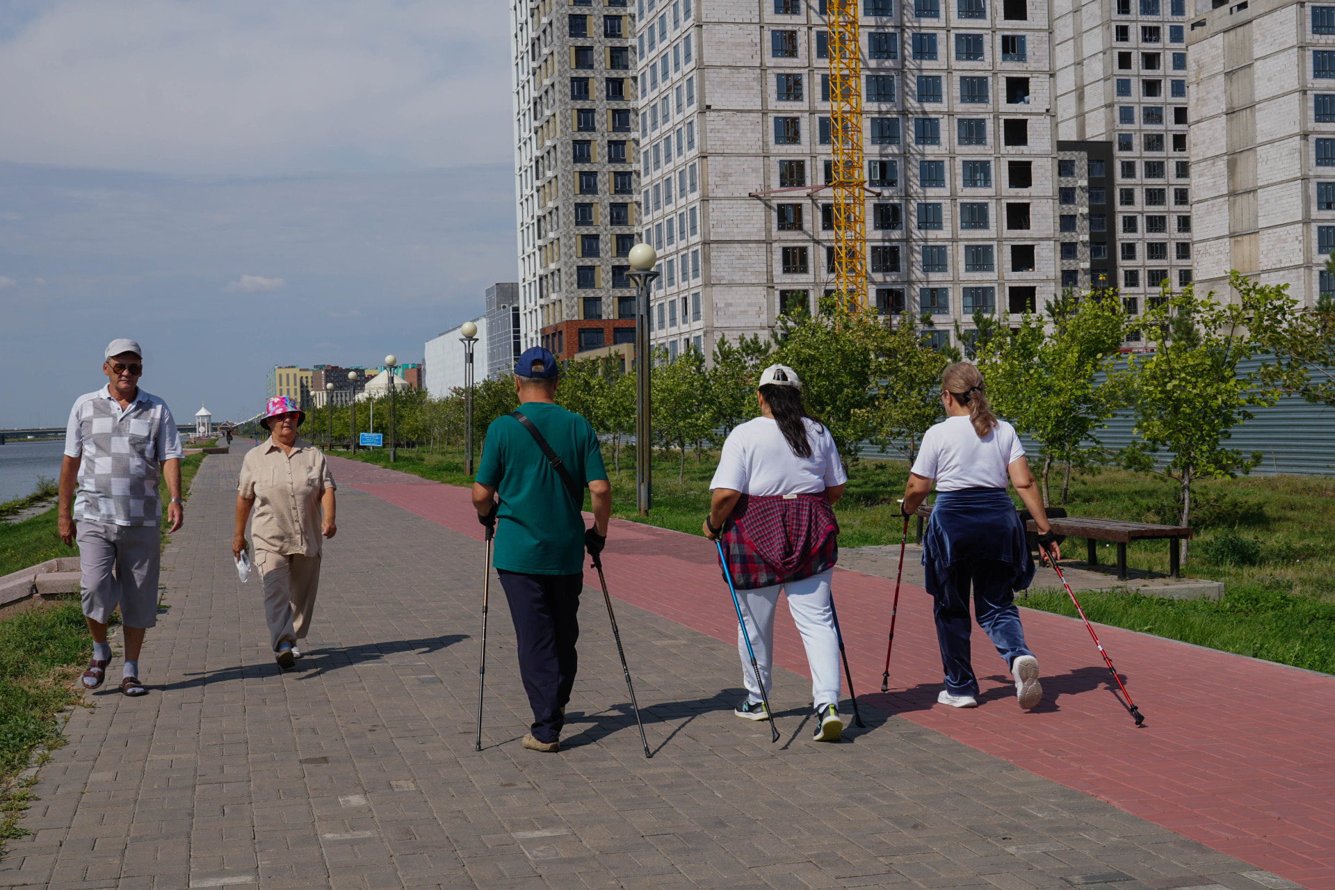Люди занимаются скандинавской ходьбой, набережная Астаны