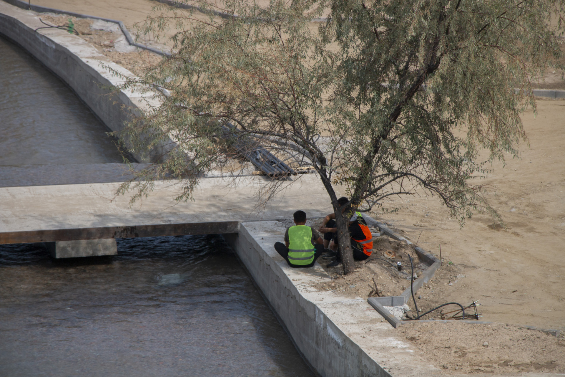 Рабочие, проводящие реконструкцию Большой Алматинке, сидят в тени деревьев, сентябрь 2025 года