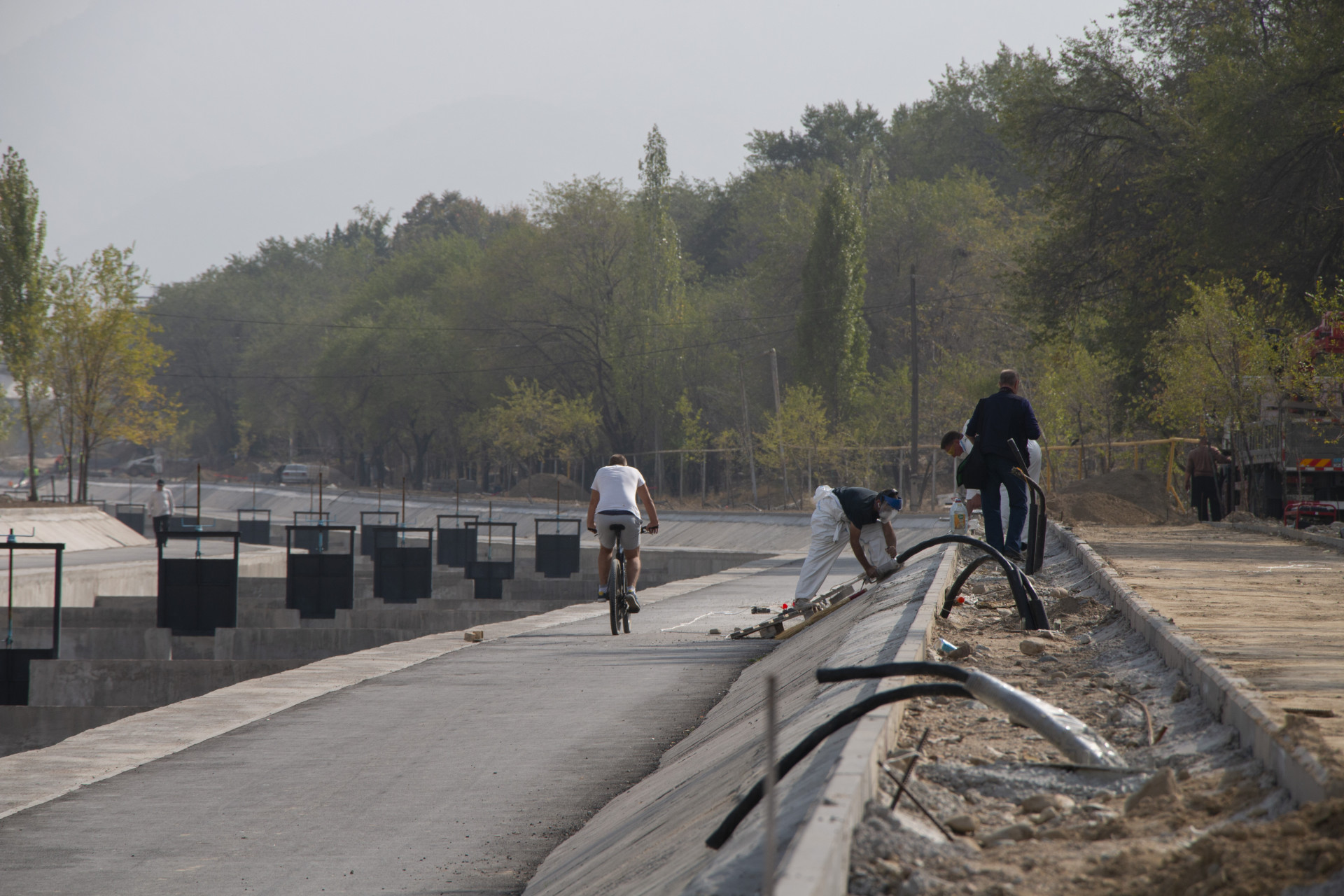 Мужчина на велосипеде едет по набережной Большой Алматинки, где ведётся реконструкция, сентябрь 2025 года