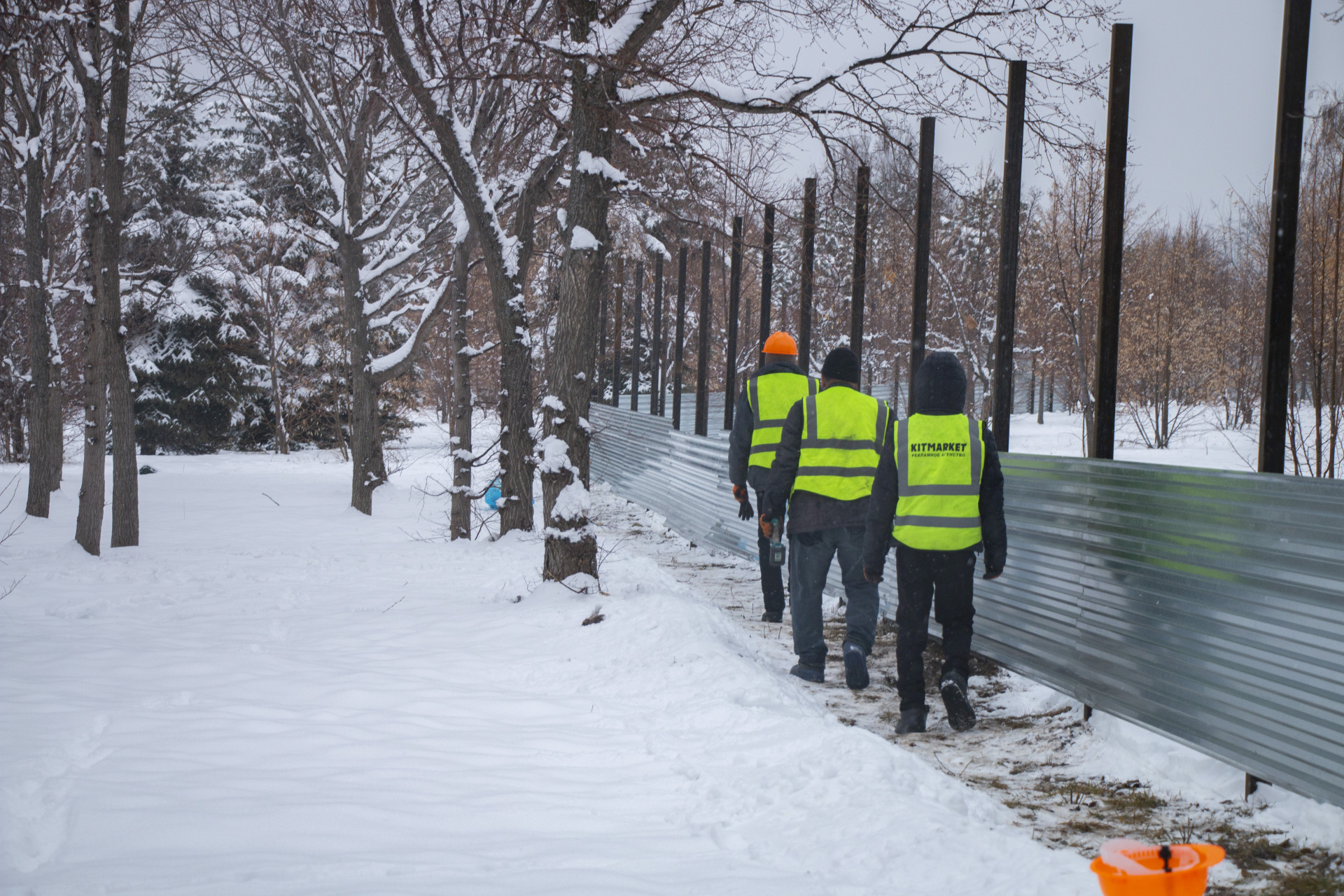 Рабочие ставят строительный забор на территории Парка первого президента в Алматы. Съёмка от 26 февраля 2026 года.