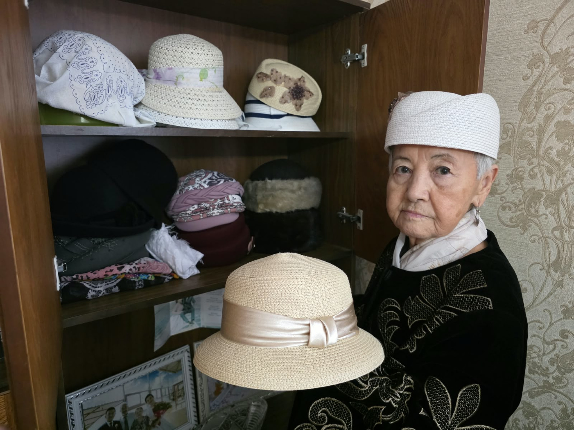 Женщина показывает шляпки, которые лежат на полке в шкафу
